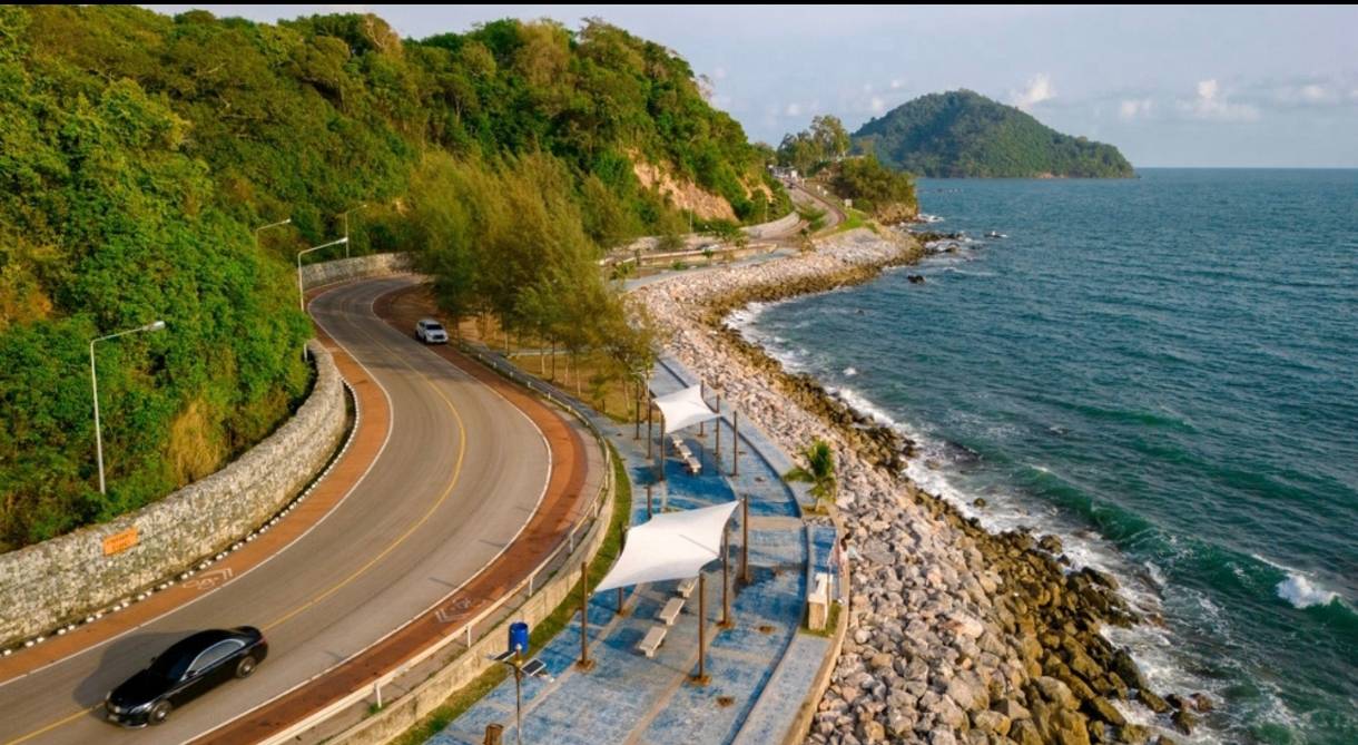 Southern Thailand coastal highway curving along the Gulf shoreline, premium transportation access to Khanom–Sichon.